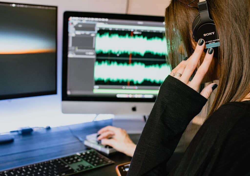 Person editing audio on a computer, highlighting the need for professional editing to avoid branded podcast mistakes.